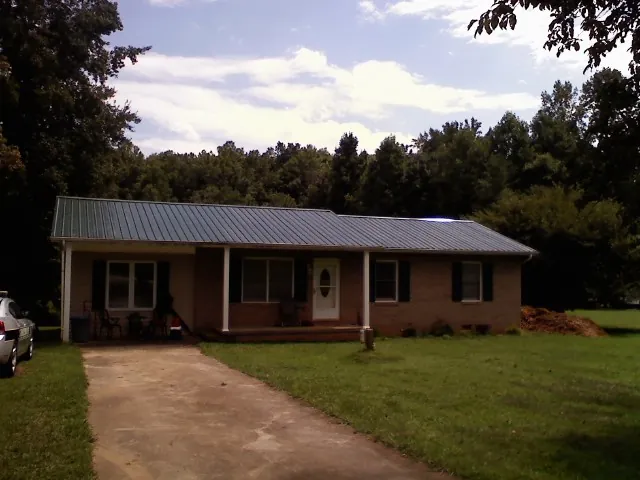 Dark green metal roof on a brick ranch with a covered porch in Newport